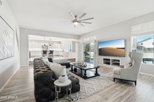 living room with a ceiling fan, visible vents, light wood-style flooring, and baseboards