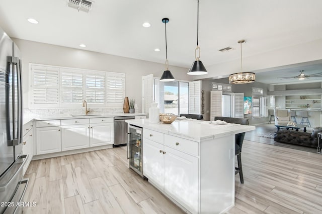 kitchen featuring pendant lighting, sink, white cabinetry, stainless steel appliances, and a center island