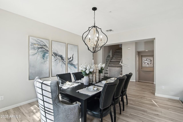 dining area featuring visible vents, baseboards, stairway, light wood-type flooring, and an inviting chandelier