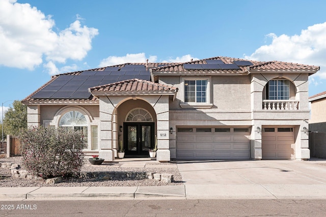 mediterranean / spanish home with french doors, a garage, and solar panels