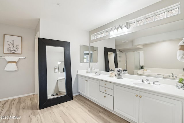 full bath with double vanity, wood finished floors, and a sink