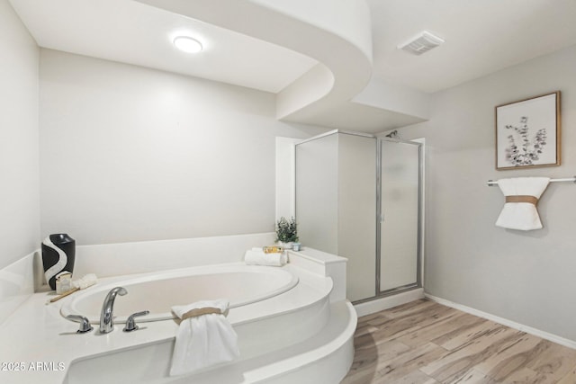 bathroom featuring a stall shower, visible vents, a bath, and wood finished floors