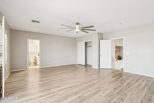 unfurnished bedroom featuring ceiling fan, ensuite bathroom, a closet, and light wood-type flooring