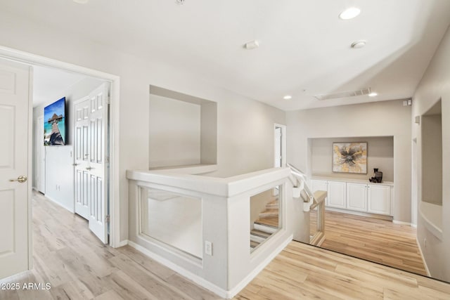 hallway featuring baseboards, light wood-style flooring, and recessed lighting