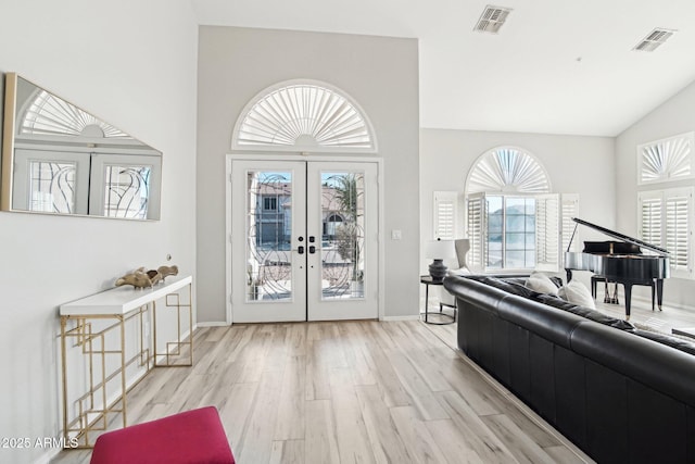 foyer with high vaulted ceiling, light hardwood / wood-style floors, and french doors