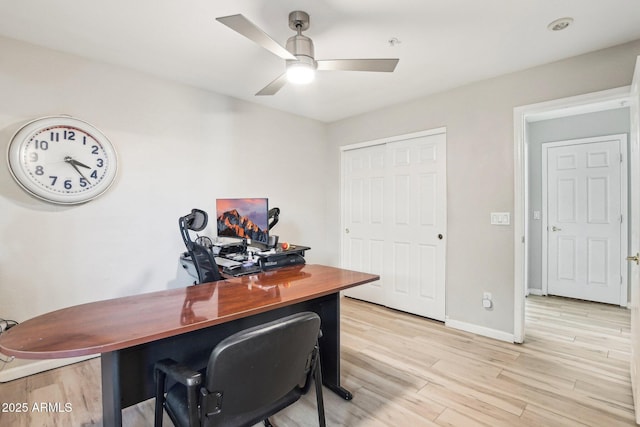 home office with light wood finished floors, a ceiling fan, and baseboards