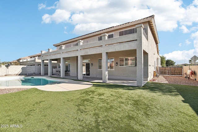 rear view of house with a fenced in pool, a yard, and a patio area