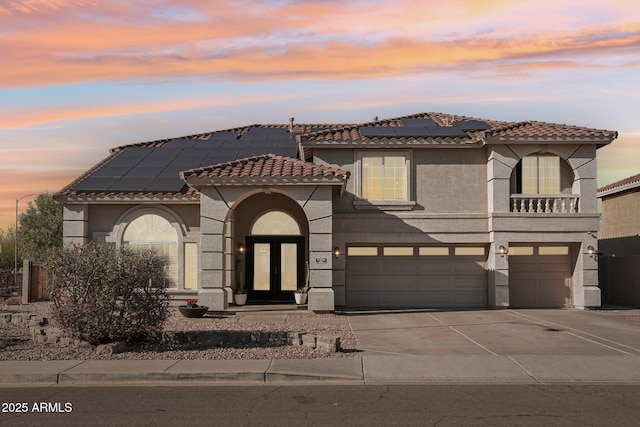 view of front facade with french doors, stucco siding, concrete driveway, an attached garage, and a tiled roof