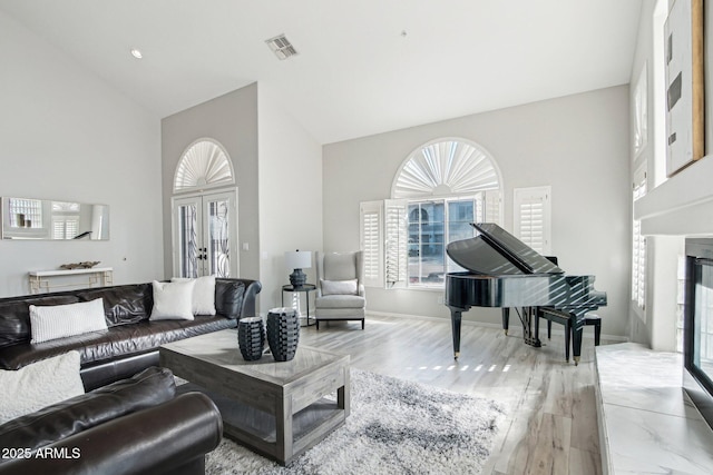 living area featuring high vaulted ceiling, french doors, a fireplace, and visible vents