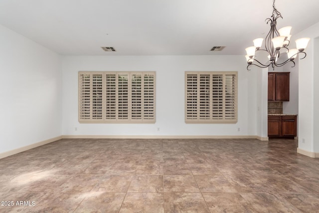 unfurnished room with a notable chandelier