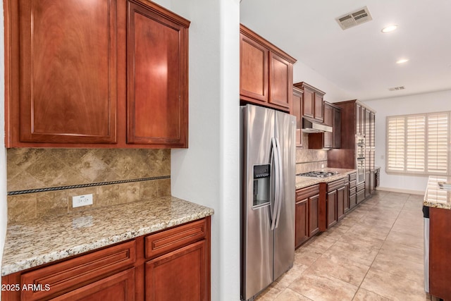 kitchen featuring light tile patterned flooring, stainless steel appliances, light stone countertops, and tasteful backsplash