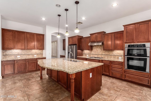 kitchen featuring a center island with sink, hanging light fixtures, a breakfast bar, sink, and appliances with stainless steel finishes