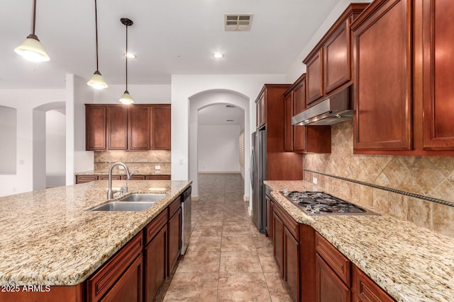 kitchen featuring sink, stainless steel appliances, hanging light fixtures, light stone countertops, and decorative backsplash