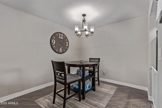 dining area featuring dark wood-style floors, baseboards, and a chandelier