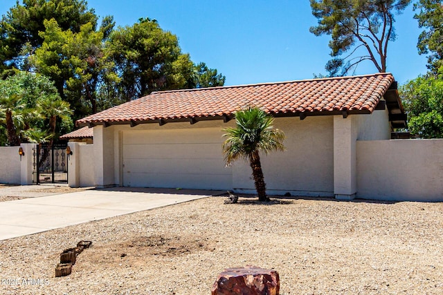 1108 N Oro Vis, Litchfield Park, AZ 85340 - mediterranean / spanish house featuring a tiled roof, a gate, driveway, an attached garage, and stucco siding