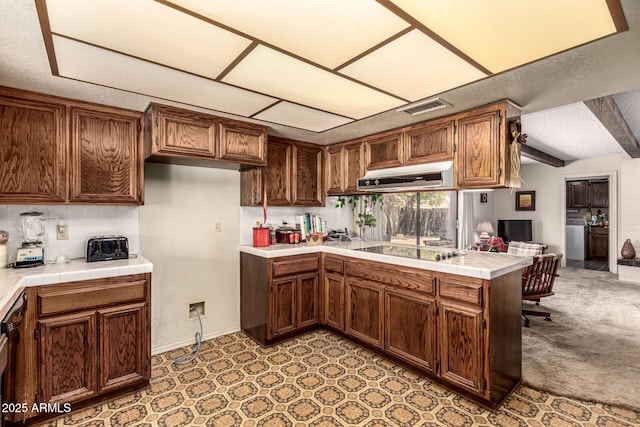 1108 N Oro Vis, Litchfield Park, AZ 85340 - kitchen with under cabinet range hood, black electric stovetop, a peninsula, tasteful backsplash, and tile counters