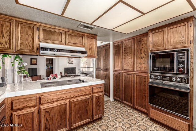 1108 N Oro Vis, Litchfield Park, AZ 85340 - kitchen featuring black appliances, under cabinet range hood, tile countertops, and brown cabinetry