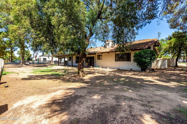 1108 N Oro Vis, Litchfield Park, AZ 85340 - rear view of house featuring stucco siding, a tiled roof, and a chimney