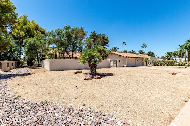 1108 N Oro Vis, Litchfield Park, AZ 85340 - view of side of home featuring stucco siding, a garage, a fenced front yard, gravel driveway, and a gate