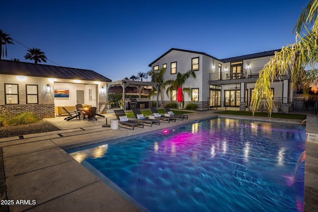 pool at dusk featuring a patio area and pool water feature