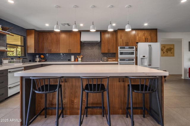 kitchen with white appliances, decorative light fixtures, a kitchen breakfast bar, and a kitchen island