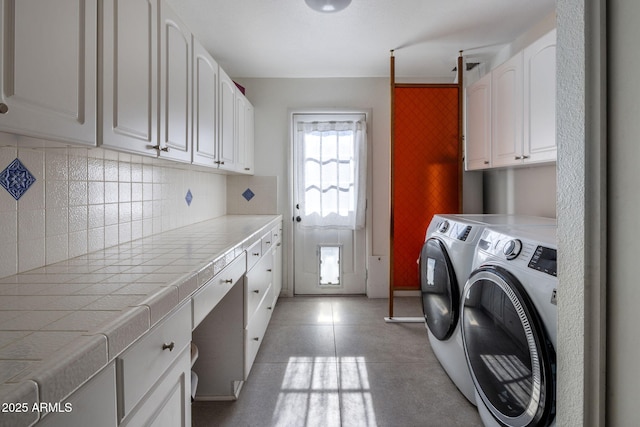 clothes washing area with cabinets and washer and dryer