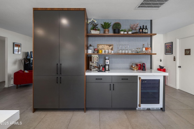 bar with wine cooler, light tile patterned floors, and gray cabinets