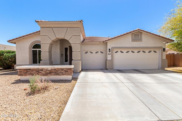 mediterranean / spanish home featuring an attached garage, stucco siding, a tile roof, and concrete driveway