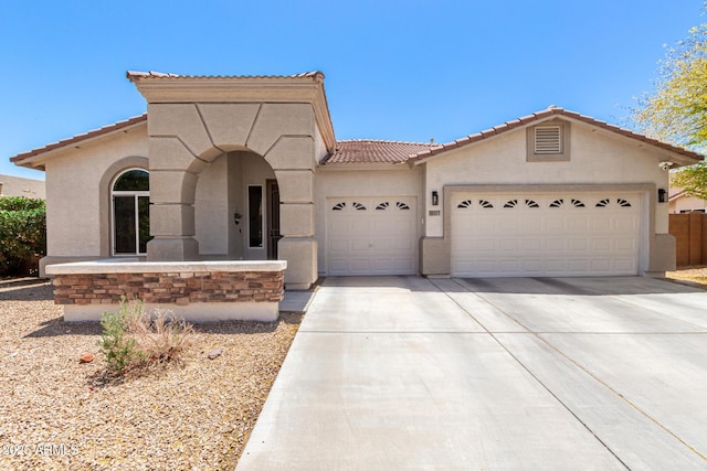 mediterranean / spanish-style home featuring stucco siding, concrete driveway, a tile roof, and a garage