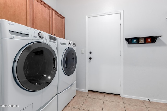washroom featuring light tile patterned floors, baseboards, cabinet space, and independent washer and dryer