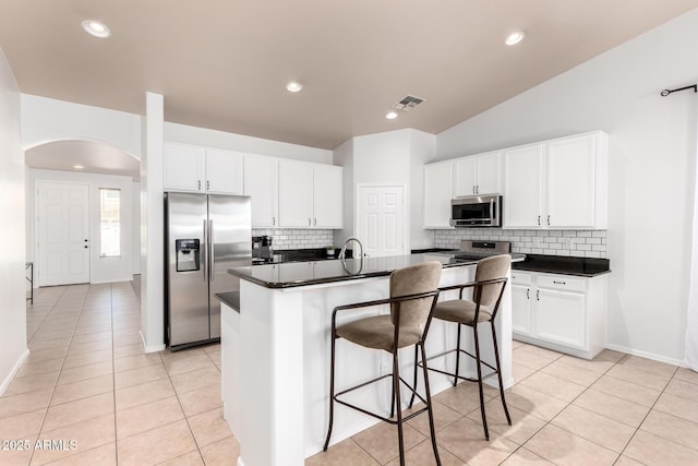 kitchen with dark countertops, backsplash, stainless steel appliances, and visible vents