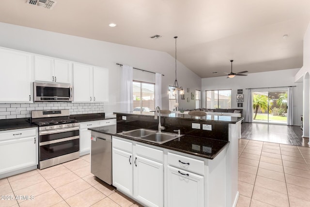 kitchen featuring lofted ceiling, light tile patterned flooring, open floor plan, a sink, and stainless steel appliances