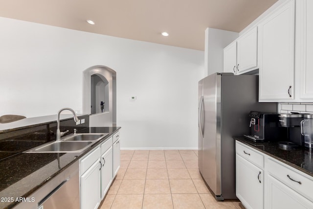 kitchen with a sink, appliances with stainless steel finishes, white cabinets, and dark stone countertops
