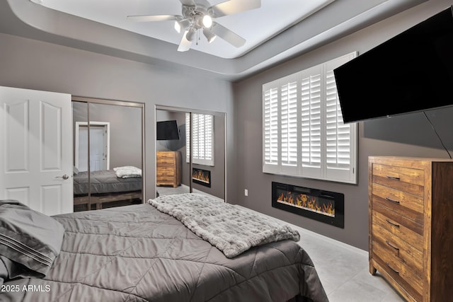 8540 E Mcdowell Rd Unit 10, Mesa, AZ 85207 - bedroom featuring baseboards, a ceiling fan, a glass covered fireplace, and two closets