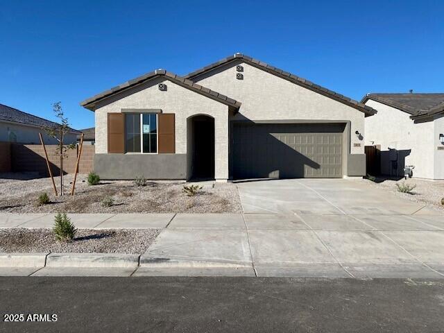 view of front of house with stucco siding, an attached garage, driveway, and a tile roof