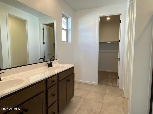 bathroom with tile patterned floors, double vanity, baseboards, and a sink