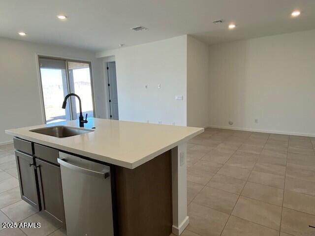 kitchen featuring stainless steel dishwasher, light countertops, recessed lighting, and a sink