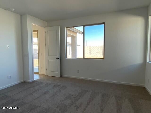 carpeted empty room with baseboards