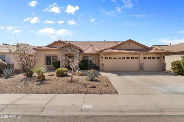 mediterranean / spanish home featuring an attached garage, a tile roof, stucco siding, stone siding, and driveway