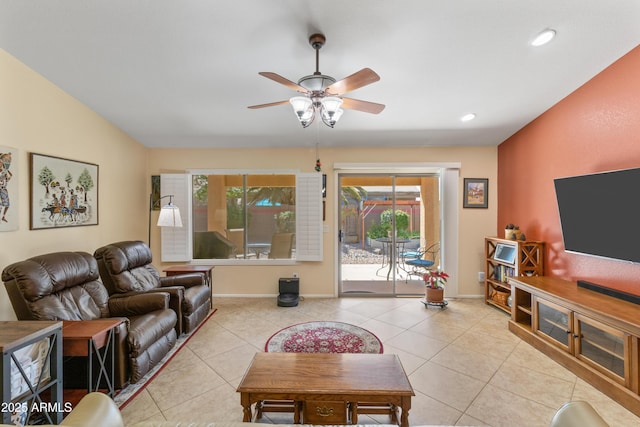 living area featuring light tile patterned floors, baseboards, and ceiling fan