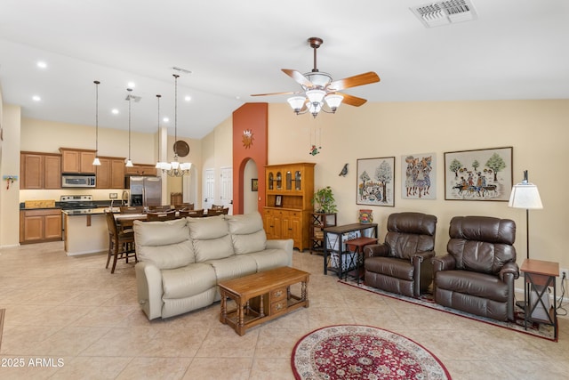 living room with light tile patterned floors, visible vents, high vaulted ceiling, arched walkways, and ceiling fan