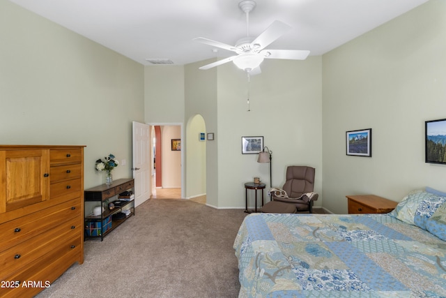 carpeted bedroom with a ceiling fan, baseboards, visible vents, and high vaulted ceiling