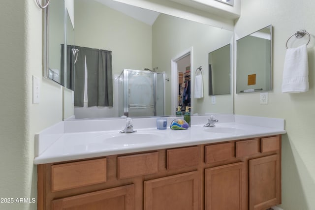 full bathroom with double vanity, a stall shower, a walk in closet, and a sink