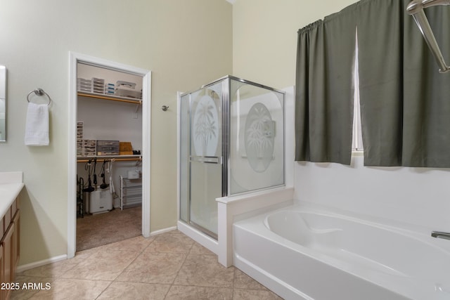 full bathroom featuring a walk in closet, a stall shower, tile patterned flooring, a bath, and vanity