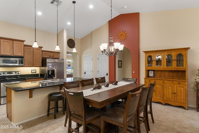 dining area with light tile patterned flooring, visible vents, arched walkways, and high vaulted ceiling