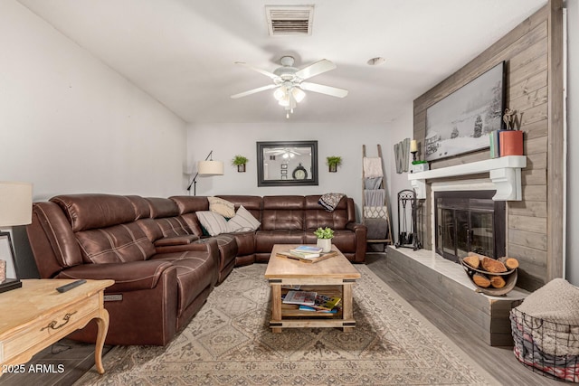 living room with hardwood / wood-style flooring, ceiling fan, and a fireplace