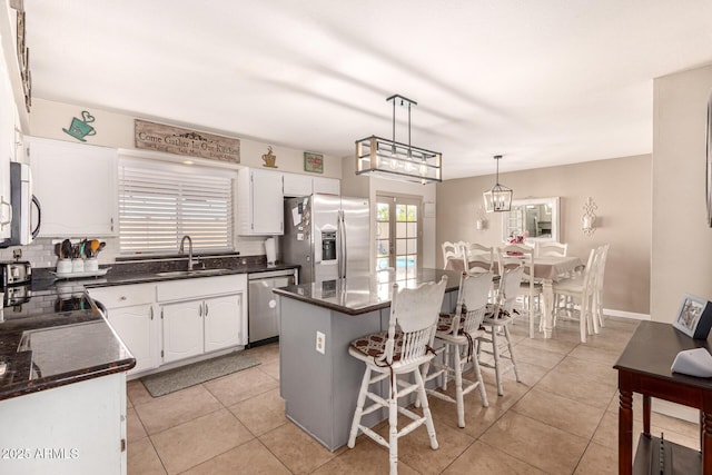 kitchen with stainless steel appliances, sink, decorative light fixtures, a center island, and white cabinetry