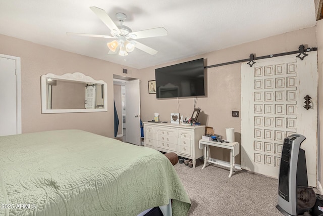 carpeted bedroom featuring a barn door and ceiling fan