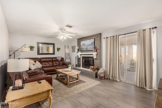 living room with ceiling fan and a fireplace