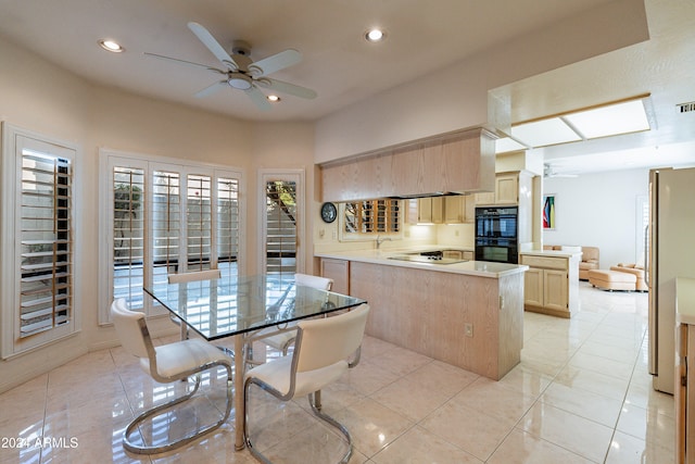 kitchen featuring black appliances, light tile patterned floors, kitchen peninsula, and light brown cabinetry